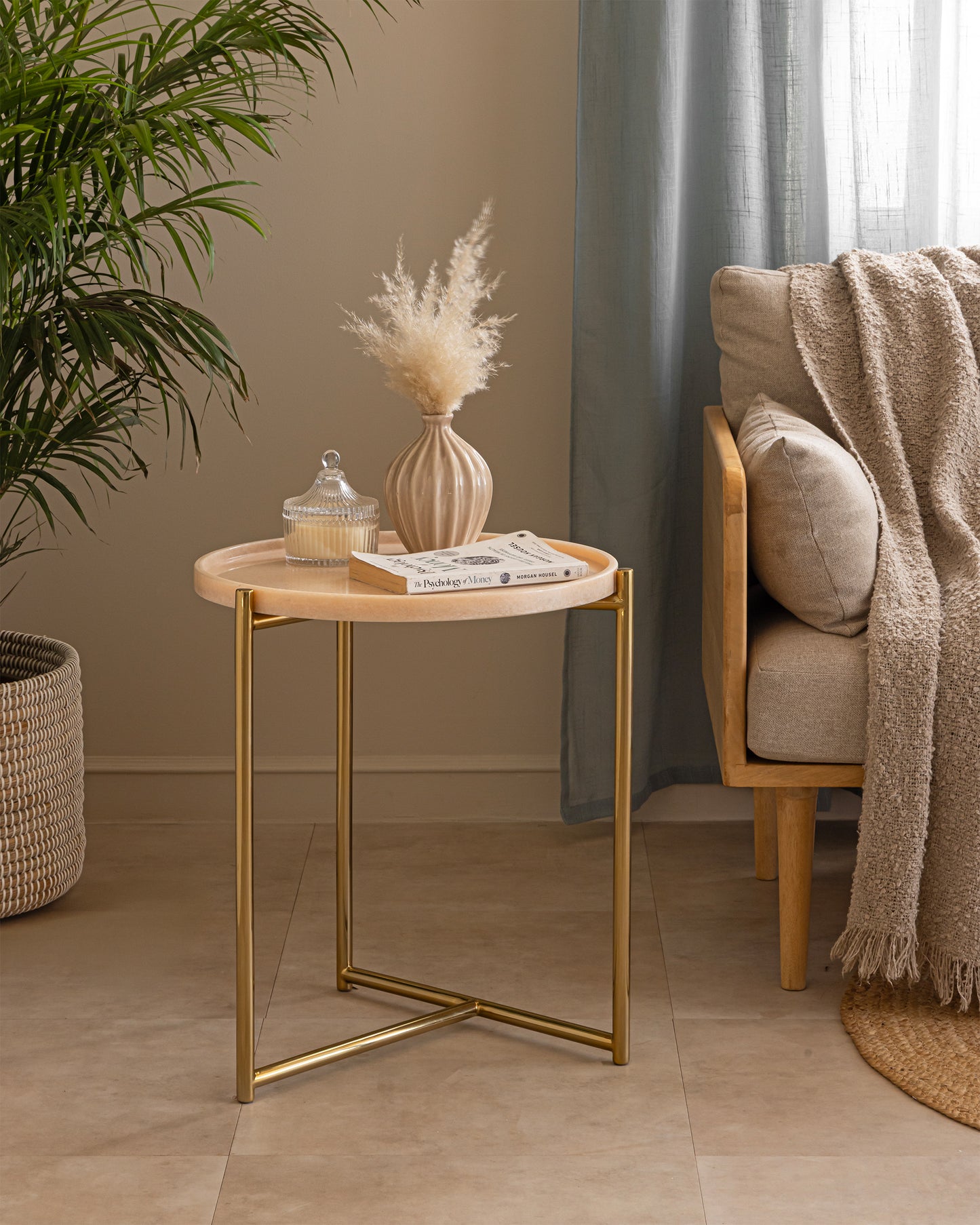 Tri Metal side table styled with a candle, vase and books beside a sofa, set in a boho living room