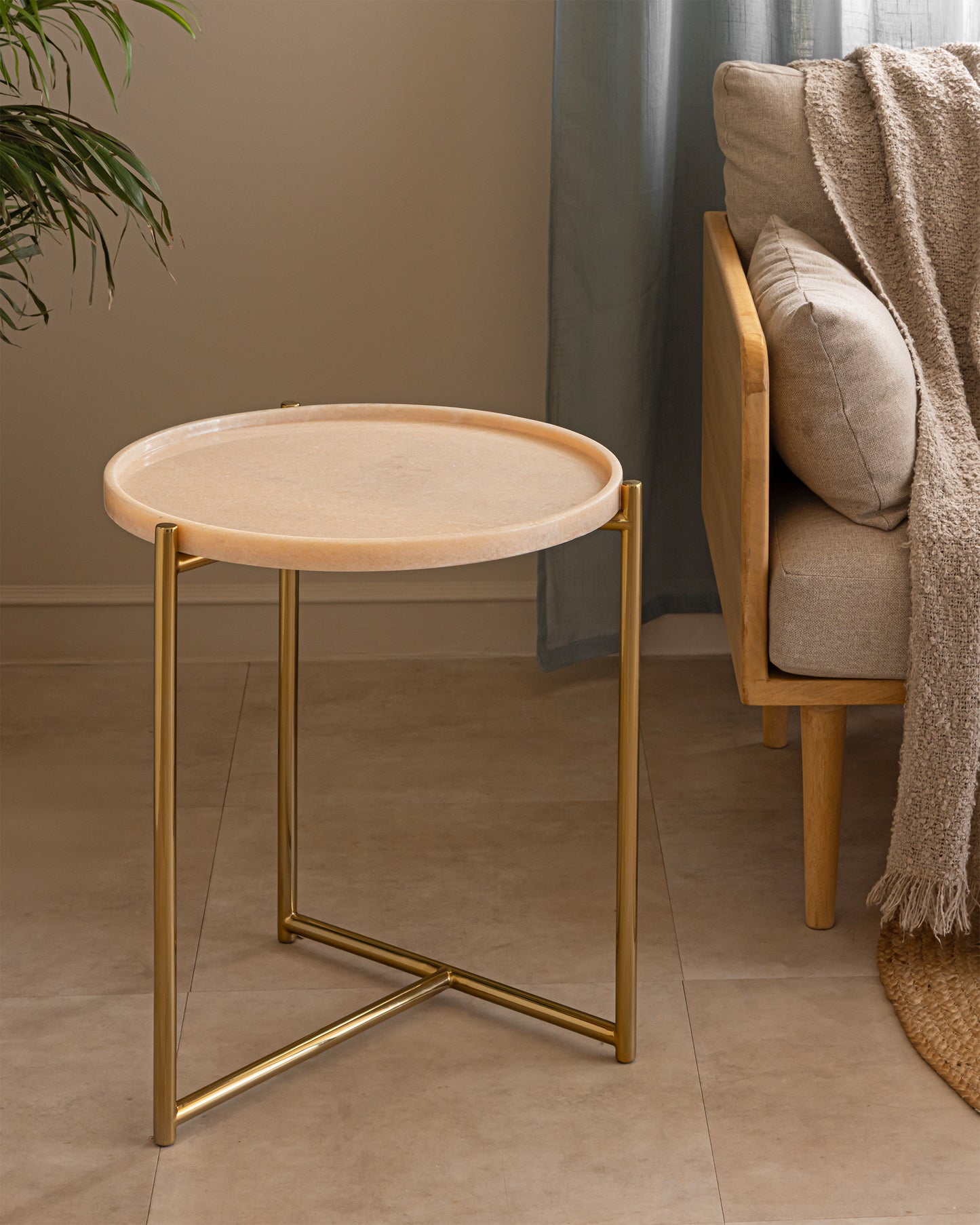 Tri Metal brass and pink marble side table beside a linen sofa in a warm neutral living room