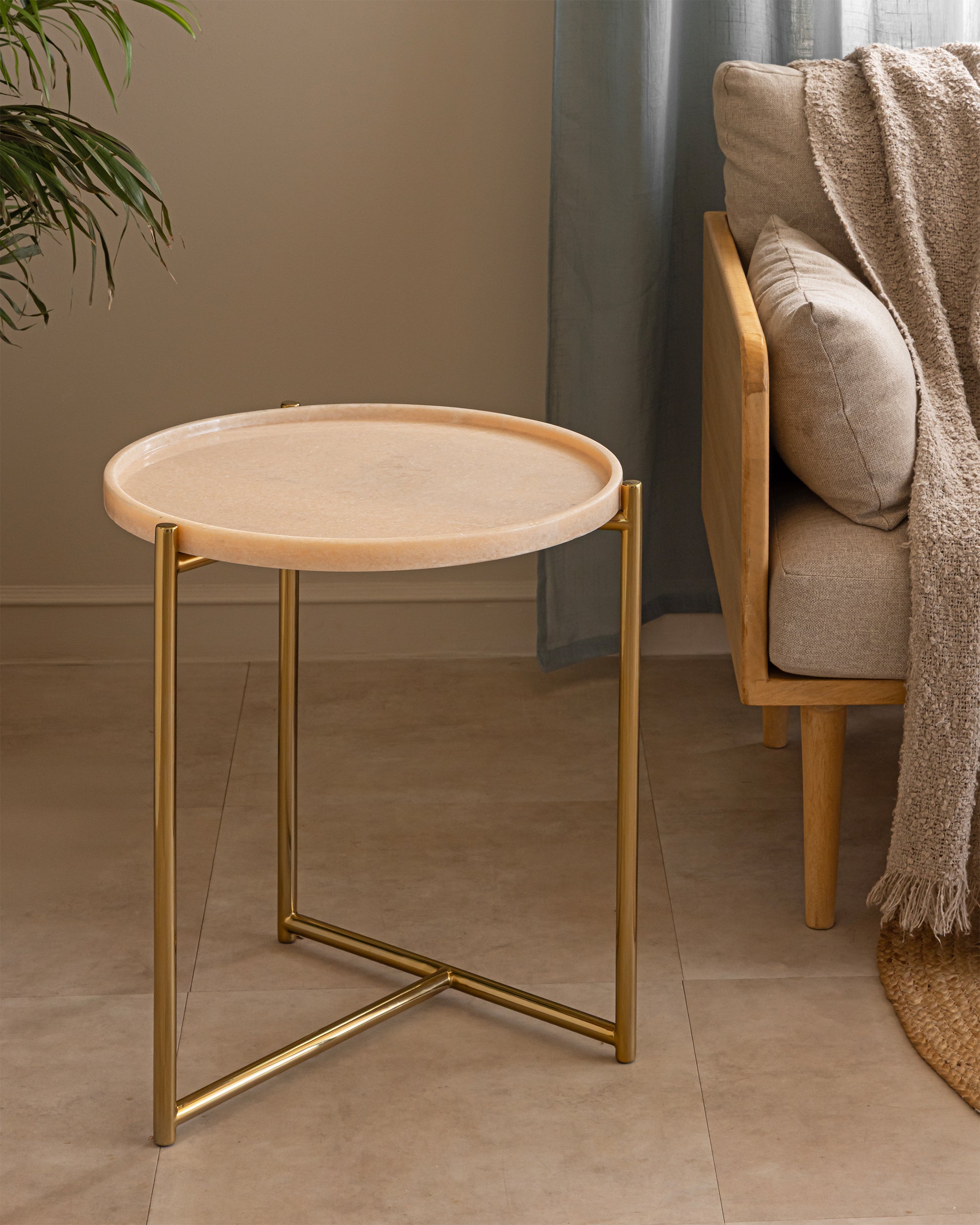 Tri Metal brass and pink marble side table beside a linen sofa in a warm neutral living room