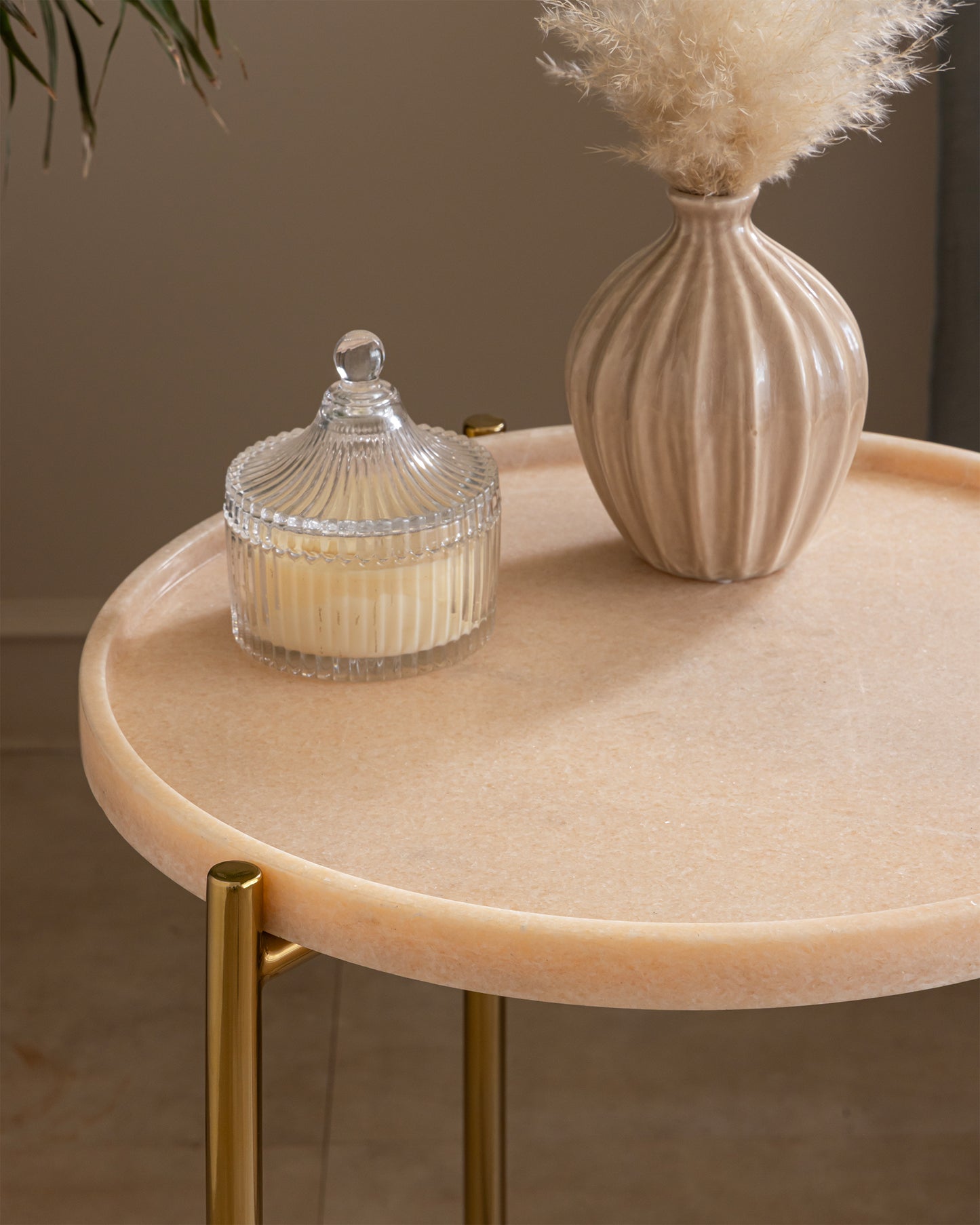 Tri Metal side table styled with a ribbed glass candle and a pampas-grass vase on its pink marble tray top